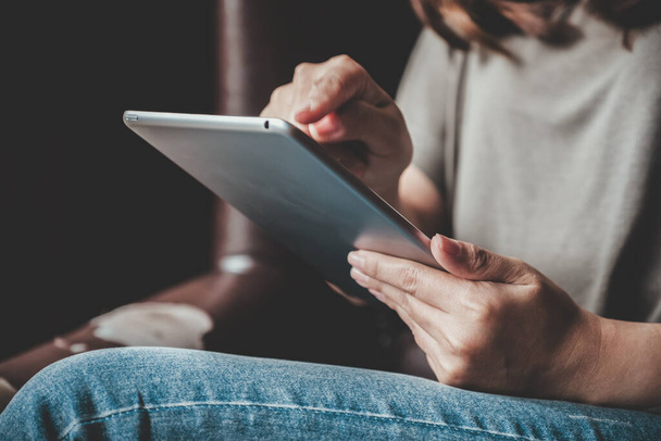 Nahaufnahme einer Frau, die in einem modernen Café einen Tablet-PC hält, benutzt und auf diesen zeigt - Foto, Bild