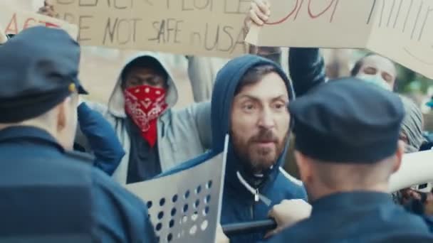 Junger kaukasischer Demonstrant schreit und schreit Polizisten bei einer Demonstration für Menschenrechte an. US-Demonstrant kämpft und streitet mit Polizisten bei Protest gegen Polizeigewalt und Rassismus. - Filmmaterial, Video