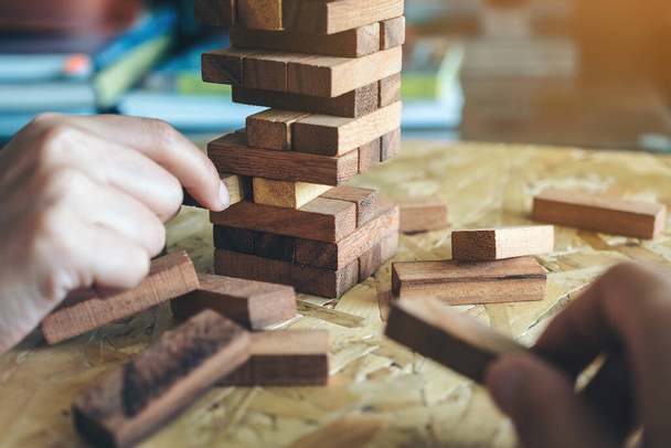 El ele tutuşup Tumble kulesi tahta blok oyunu oynarken yakın plan görüntüsü - Fotoğraf, Görsel