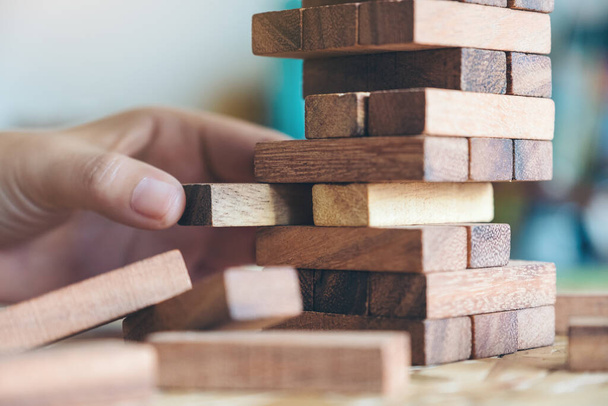 Closeup image of a hand holding and playing Tumble tower wooden block game - Φωτογραφία, εικόνα