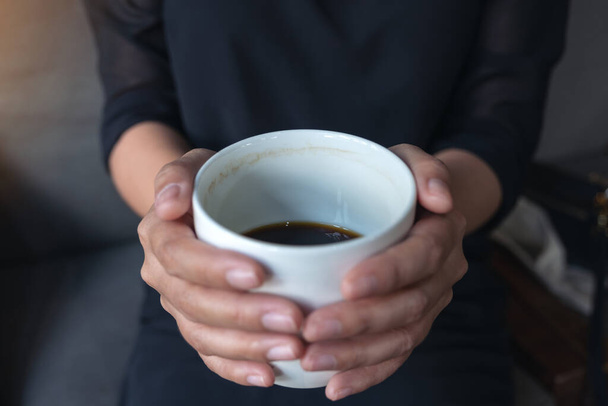 Imagen de cerca de las manos de una mujer sosteniendo una taza blanca de café caliente
  - Foto, imagen
