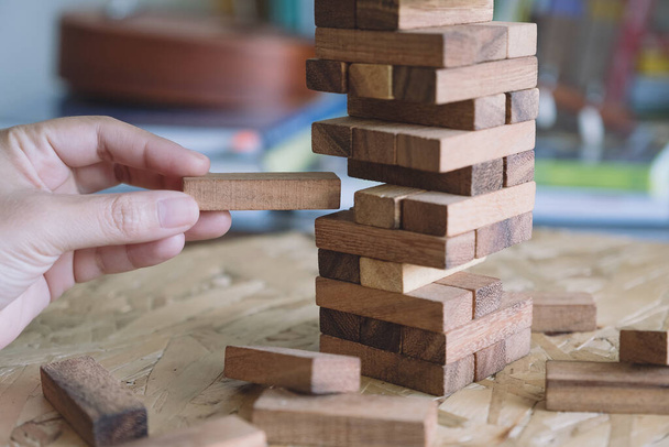 Close-up afbeelding van een hand houden en spelen Tumble toren houten blok spel - Foto, afbeelding