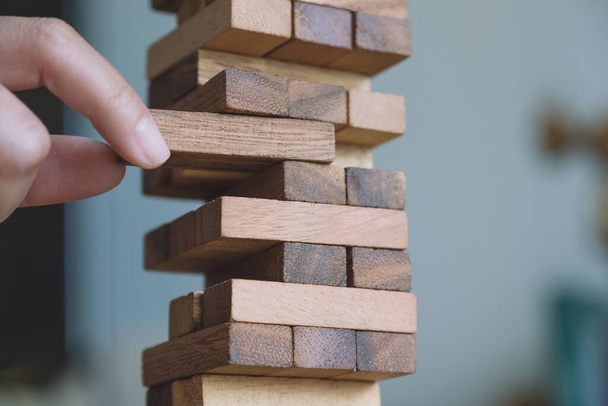 Imagem de close-up de uma mão segurando e jogando torre Tumble jogo de bloco de madeira - Foto, Imagem
