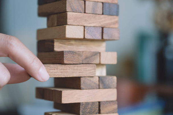 Closeup image of a hand holding and playing Tumble tower wooden block game - Φωτογραφία, εικόνα
