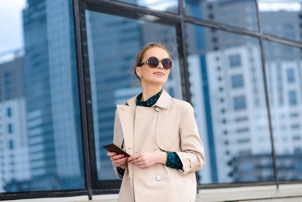Young beautiful businesswoman with sunglasses, phone, laptop, cup of coffee in the city street - Φωτογραφία, εικόνα