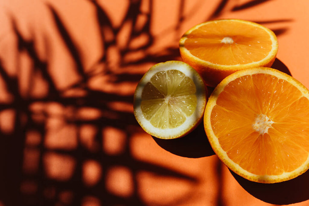 Summer tropical composition. Shadow of palm leaves and tropical fruits on orange background. - 写真・画像