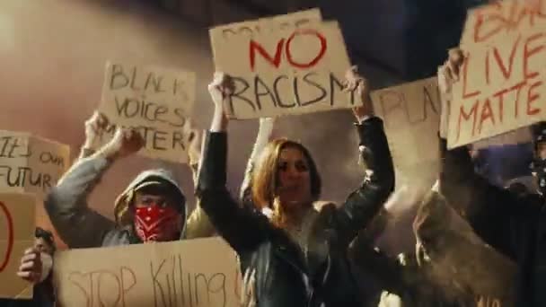 Jovens e jovens manifestantes multiétnicos em fumaça gritando motos e slogans com cartazes para os negros dignidade na manifestação à noite. Manifestação e rebelião nos EUA na rua
. - Filmagem, Vídeo