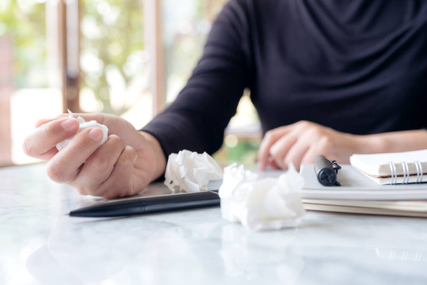 Closeup image of business woman working and squeezing papers on the table with feeling stressed and upset - Foto, afbeelding