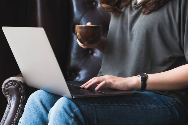 Immagine ravvicinata di una donna che lavora, utilizza e digita sulla tastiera del computer portatile mentre beve caffè
 - Foto, immagini