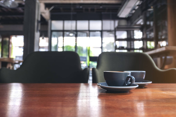 Closeup image of two blue cups of hot latte coffee on vintage wooden table in cafe - Photo, Image