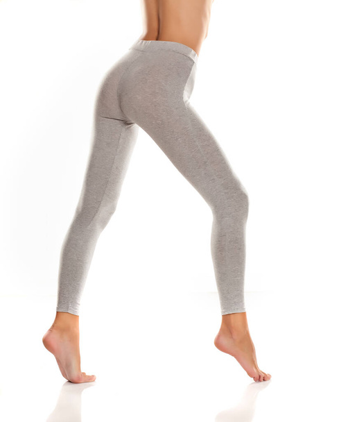 sexy slim female buttocks and legs in gray leggingss on white background - Foto, Imagen