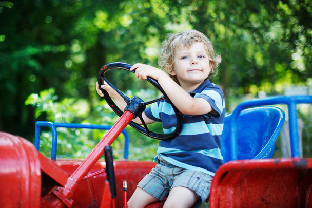 Portrait of little blond boy in tractor in summer - Photo, Image