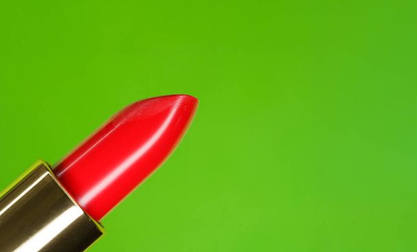 Hermoso lápiz labial rojo brillante y color verde complementario en el fondo
 - Foto, Imagen