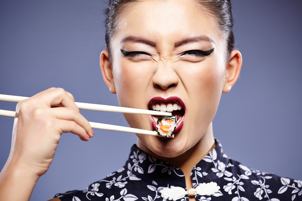 Sushi woman holding sushi with chopsticks looking at the camera - Valokuva, kuva