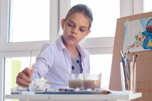 少女芸術家は静物画のための塗料でぬれたブラシを集中 - 写真・画像