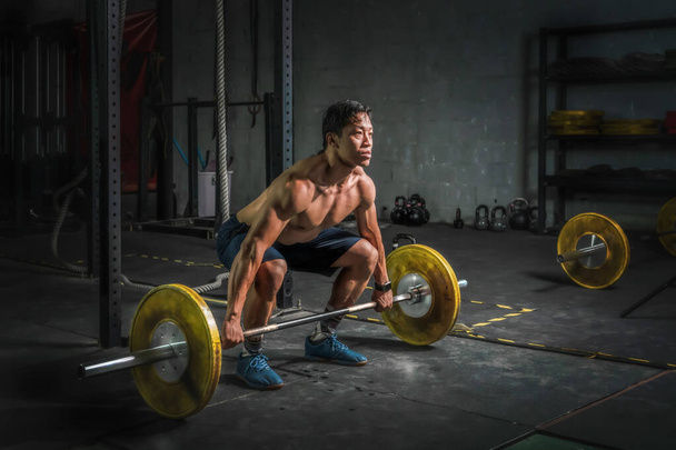 asian strong athletic man having workout and bodybuilding with barbells weight lift clean setting style in gym and fitness club in dark tone - Fotoğraf, Görsel