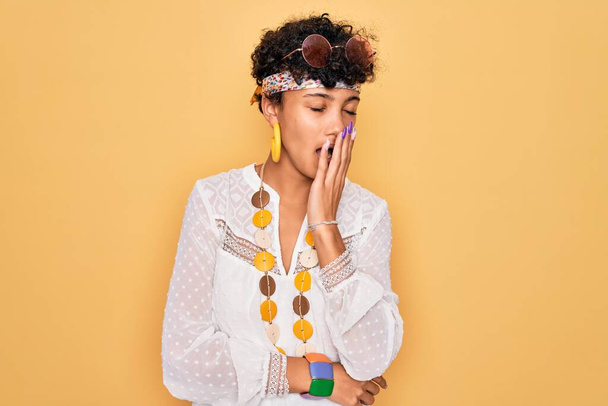 Young beautiful african american afro hippie woman wearing sunglasses and accessories bored yawning tired covering mouth with hand. Restless and sleepiness. - 写真・画像