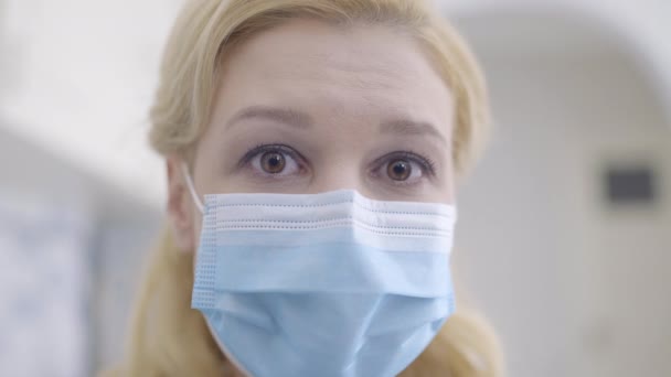 Worried woman in mask looking at camera, feeling depressed during quarantine - Кадры, видео