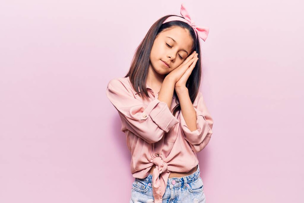 Beautiful child girl wearing casual clothes sleeping tired dreaming and posing with hands together while smiling with closed eyes.  - Foto, Imagen