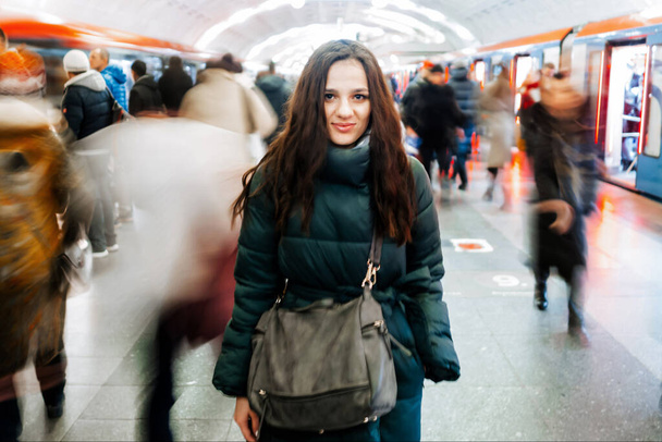 Jong blank meisje op een metrostation en een menigte van bewegende mensen met vervaging - Foto, afbeelding