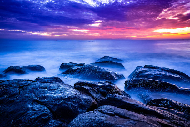 Gyönyörű napfelkelte a tengerpart felett, hosszú kitéve. Mozgó elemek napkelte és hullám fotózás a sziklás strand Indiában. Piros ég öbölben bengáli, lassú redőny Tengeri hullámok és sziklák fotózás. - Fotó, kép