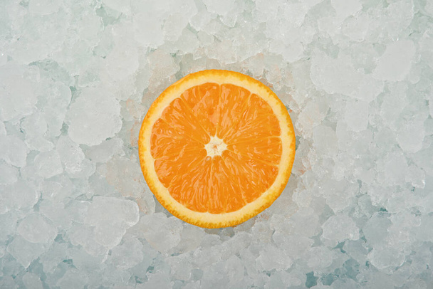 Feche uma laranja suculenta fresca cortada meia fatia sobre o fundo do gelo picado, vista de alto ângulo elevada, diretamente acima
 - Foto, Imagem