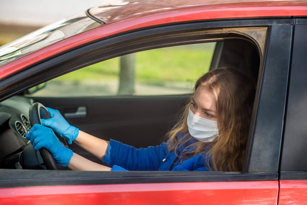 A woman driving a car in a protective medical mask and gloves. Lifestyle and safe drive during a pandemic coronavirus in quarantine. Protect the driver and passengers. New normal and modern reality - Foto, Imagem