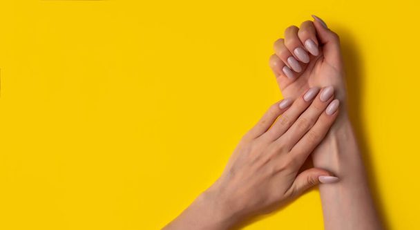 Female hands with a beautiful manicure on a yellow background,top view,flat lay. Manicure concept,banner - Φωτογραφία, εικόνα