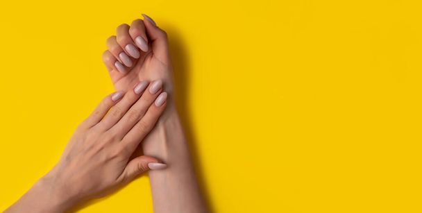 Female hands with a beautiful manicure on a yellow background,top view,flat lay. Manicure concept,banner - Fotografie, Obrázek
