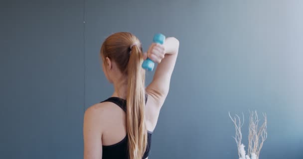Вид ззаду на тренування дівчини з гантелями вдома
 - Кадри, відео