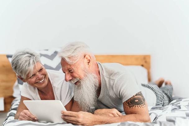 Feliz pareja de personas mayores utilizando tableta digital en la cama - Las personas maduras que tienen divertido tiempo de la cama juntos - Ancianos relación de amor estilo de vida y el concepto de tecnología - Foto, imagen