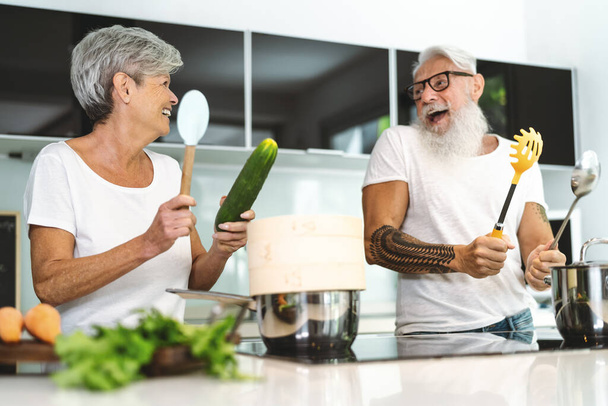 Mutlu son sınıf çifti evde birlikte yemek pişirirken eğleniyor - modern mutfakta öğle yemeği hazırlayan yaşlı insanlar - emekli yaşam tarzı aile zamanı ve gıda beslenme konsepti - Fotoğraf, Görsel