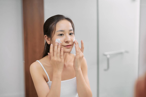 Woman happy cleanses the skin with foam in bathroom. - Zdjęcie, obraz