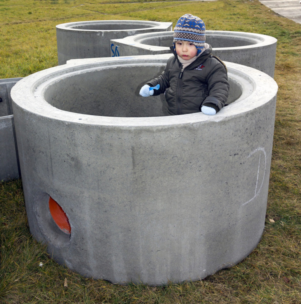 Menino de pé dentro de um grande tubo de concreto
 - Foto, Imagem