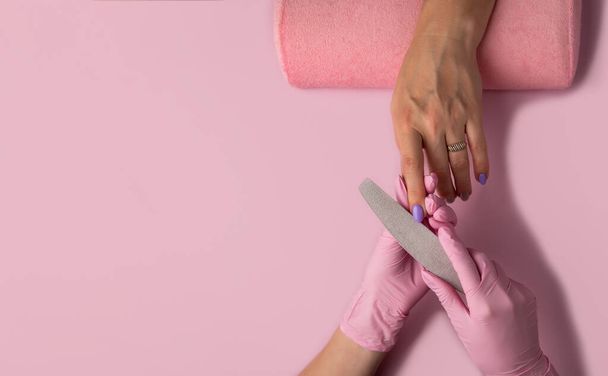 Manicure process, top view.Manicure in beauty salon.Manicure concept, flat lay. manicurist uses nail file. Selective focus on costumer's nails. - Foto, Imagem