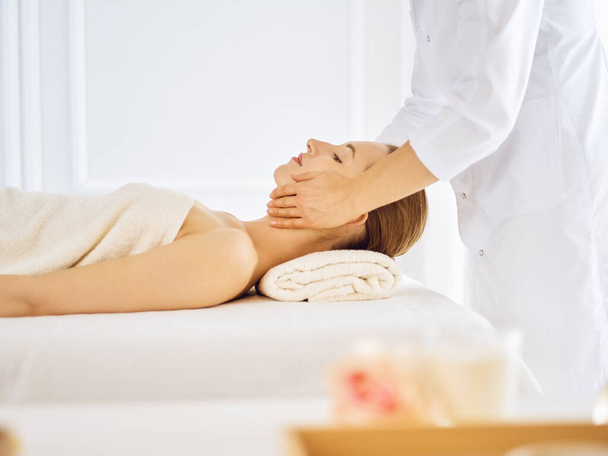 Beautiful woman enjoying facial massage with closed eyes - Фото, зображення