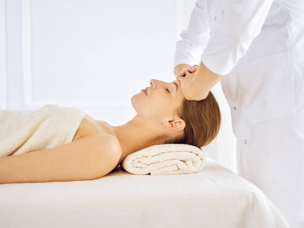 Beautiful woman enjoying facial massage with closed eyes - Фото, зображення