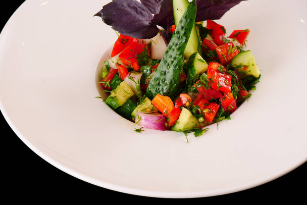 Choban salad. Cucumber and tomato salad with greens. Black background - Foto, imagen