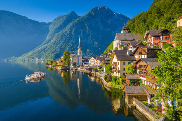 風光明媚な絵葉書。夏の晴れた日に美しい朝の光の中で旅客船とオーストリアアルプスの有名なハルシュタットの山の村の景色,ザルツカンマーグート地方,オーストリア - 写真・画像