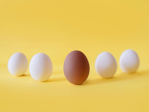 Dark and white eggs on the yellow background. Black lives matter, diversity,  equal rights concept - Φωτογραφία, εικόνα