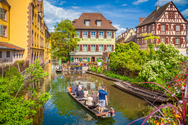 Beautiful view of the historic town of Colmar, also known as Little Venice, with tourists taking a boat ride along traditional colorful houses on idyllic river Lauch in summer, Colmar, Alsace, France - Photo, Image