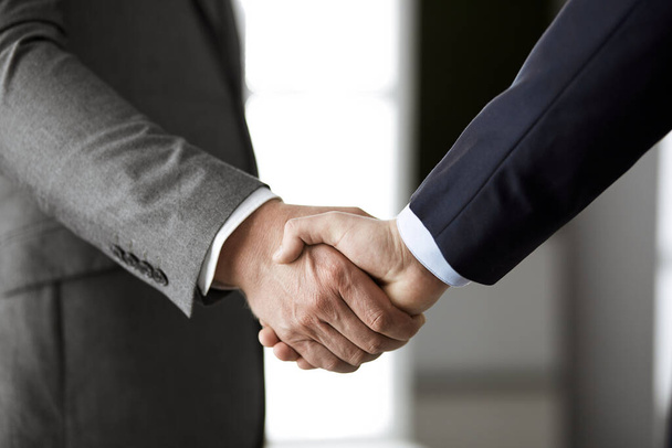Business people in office suits standing and shaking hands, close-up. Business communication concept. Handshake and marketing - Foto, immagini