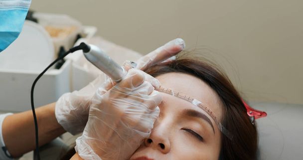 Frau unterzieht sich Augenbrauen-Microblading, Permanent Make-up - Foto, Bild