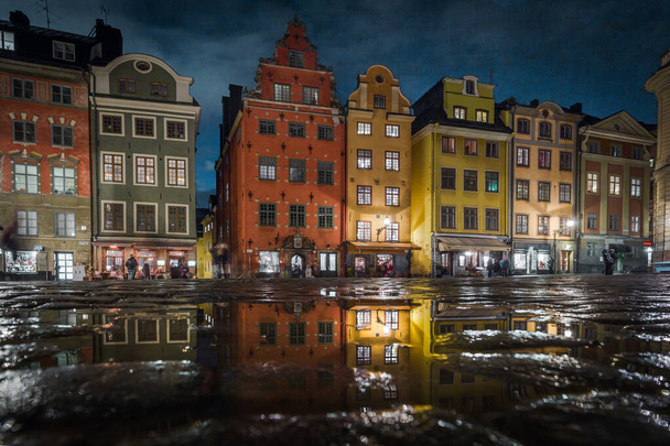 Vue classique de maisons colorées sur la célèbre place Stortorget dans le Gamla Stan (Vieille Ville) historique de Stockholm reflétant dans une flaque d'eau avec ciel bleu, centre de Stockholm, Suède - Photo, image