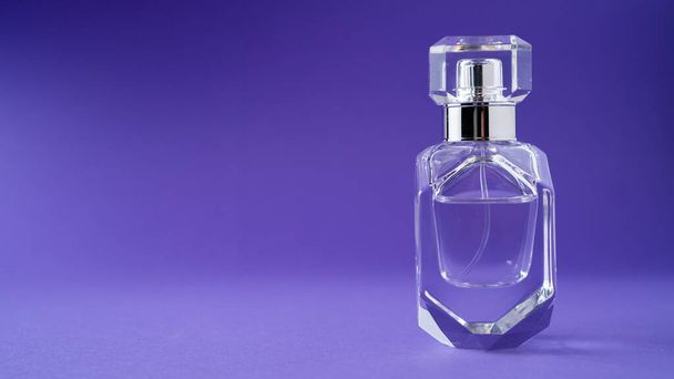 Modeparfüm in Glasflasche auf lila Hintergrund. Diamantflaschenform. Transparente Flasche. Kristall. Isoliert - Foto, Bild