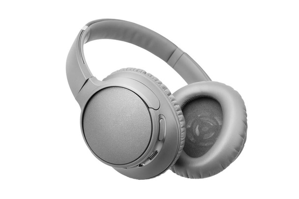 白い背景にグレーのワイヤレスヘッドフォンを隔離されたクローズアップ、大きな革の耳パッドクッションデザインのグレーのブルートゥースヘッドセット、現代の黒のWi-Fiステレオサウンドイヤフォンサイドビュー、オーディオ音楽デバイス - 写真・画像