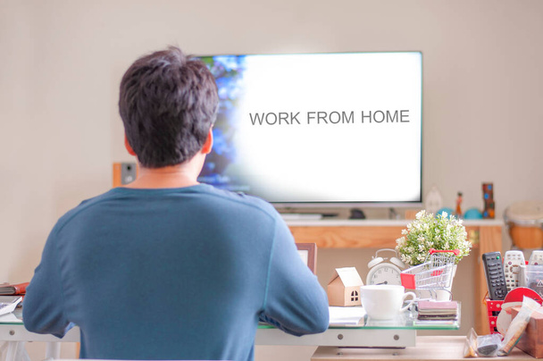 Um homem trabalha em casa. Trabalha em casa. Homem usar camisa azul sentado na sala de estar para o trabalho em casa
. - Foto, Imagem