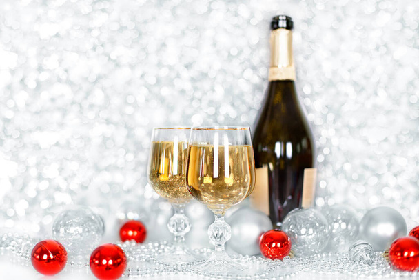 Kaksi lasillista samppanjaa ja pullo samppanjaa, uudenvuoden punaiset ja valkoiset pallot, hopeanvärinen koristelu hämärtynyt bokeh tausta, malli jouluksi ja uudenvuoden tervehdyskortti, juliste, banneri - Valokuva, kuva