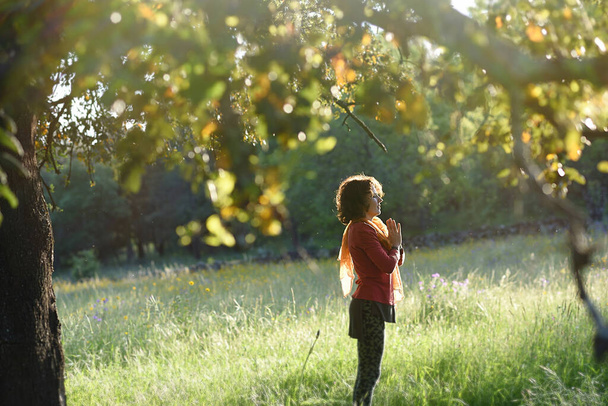 Meditierende Frau begleitet von einem großen Baum auf dem Feld. - Foto, Bild