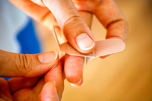 Woman putting adhesive Bandage on her finger. Close-up - Foto, Imagen